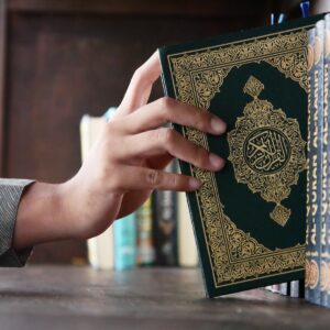 a person holding a book in front of a bookshelf