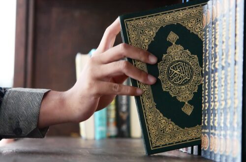 a person holding a book in front of a bookshelf