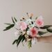 Unrecognizable male holding bunch of fresh chamomiles cloves and gerberas during making tender spring composition against beige background