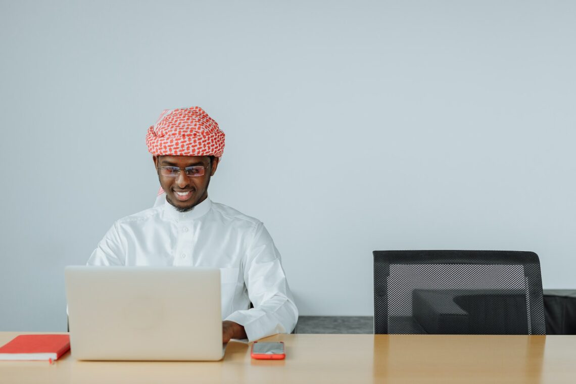 Man in White Thobe Using a Laptop