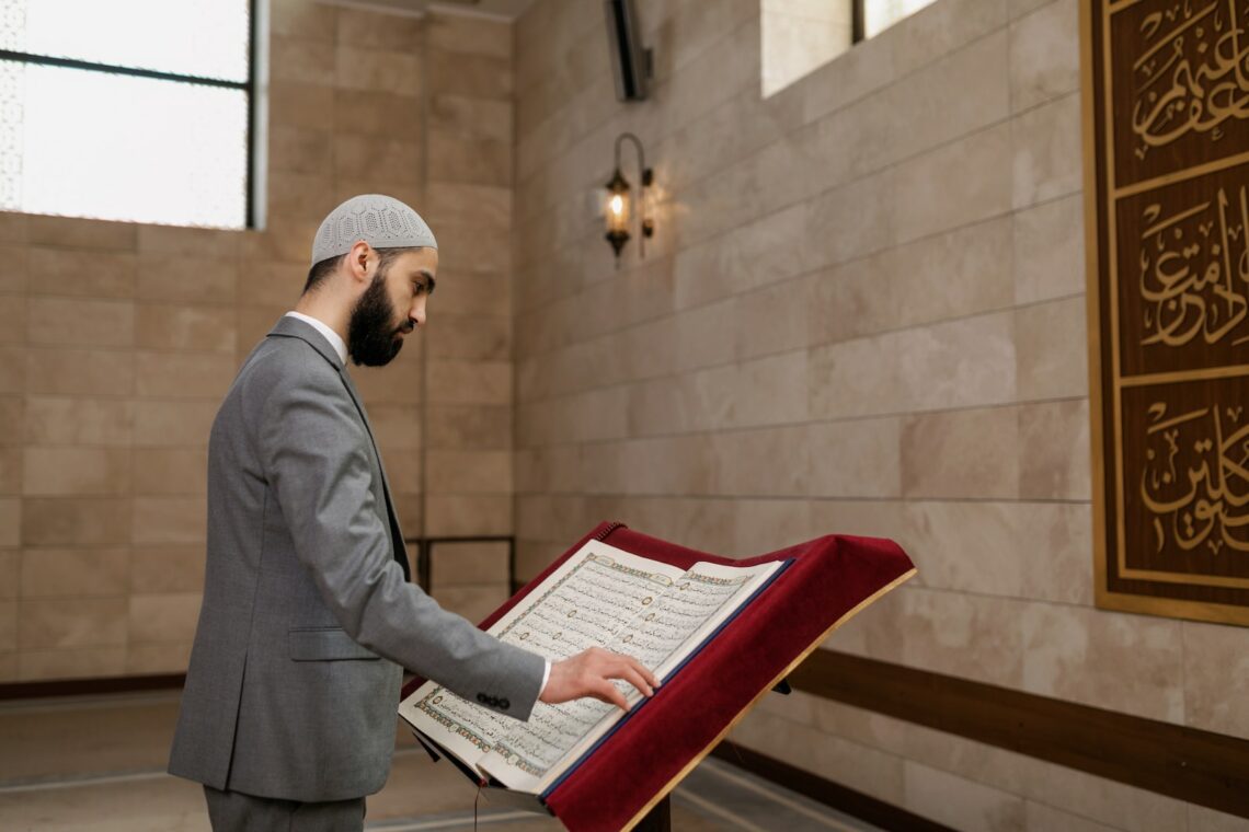 A Bearded Man in Gray Suit Reading a Koran