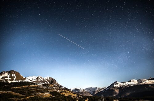 photo of shooting star over snow covered mountains