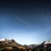 photo of shooting star over snow covered mountains