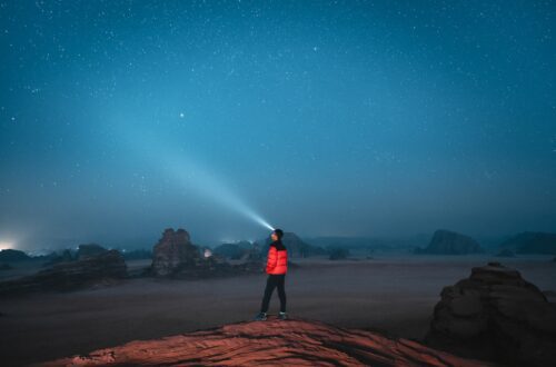 a person standing on top of a rock under a sky filled with stars