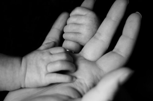 photo of baby holding person's fingers