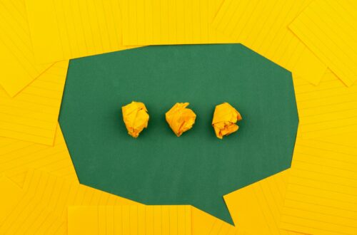 three crumpled yellow papers on green surface surrounded by yellow lined papers